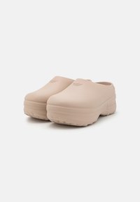 Béžové kroksy z hladké gumy s kulatou špičkou, nízkým podpatkem a texturovanou podrážkou, s jemným logem na nártu.