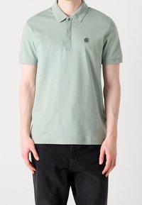 Polo de color verde claro con cuello, mangas cortas y un pequeño logo en el pecho. Hecho de una tela suave con un corte estándar.
