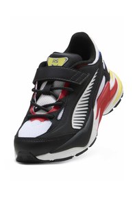 Chaussure de sport noire, rouge et blanche avec tige en mesh, col rembourré et sangle ajustable. Logo jaune notable sur la languette et semelle texturée.