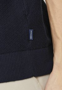 Maglione lavorato a maglia blu navy con tessuto testurizzato e orlo a coste. Presenta un piccolo etichetta blu con "JACK & JONES" sul lato.
