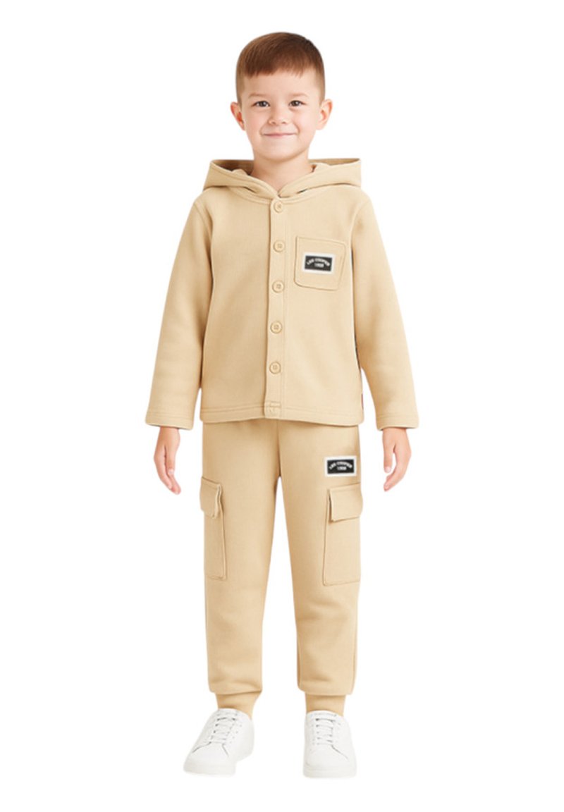 Sweat à capuche beige pour enfant avec boutons et poche, associé à un pantalon cargo assorti avec poches à rabat. Des baskets blanches complètent la tenue.