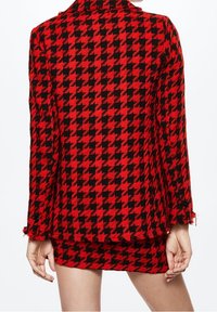 Blazer met een rood en zwart houndstooth patroon, textuurstof, rafelige zooms, op maat gemaakte pasvorm, met driekwartmouwen en een kraag.
