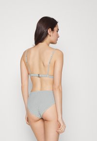 Conjunto de biquíni riscado com alças finas ajustáveis e parte de baixo de cintura alta numa palete de cores suaves, apresentando um fecho com clasp nas costas.