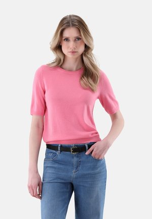 Pink short-sleeve sweater with a crew neckline, made of soft material. Worn with blue jeans and a black belt, featuring a silver buckle.