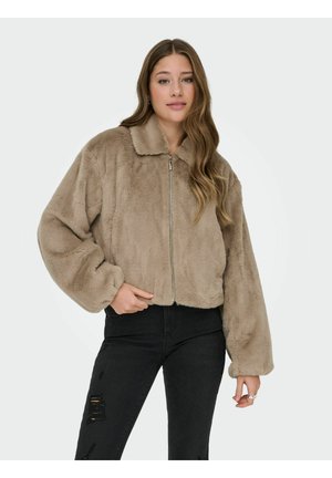 Giacca cropped in pelliccia ecologica di colore marrone chiaro con colletto e zip frontale. Presenta maniche oversize e una consistenza morbida. Abbinata a jeans neri strappati.