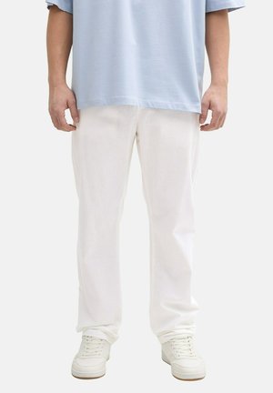 Pantalones blancos de pierna ancha con una textura sutil, combinados con una camiseta oversized de color azul claro y zapatillas blancas. Estilo simple y minimalista.