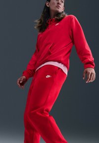 Rode hoodie met een voorvak en een wit Nike-logo, gecombineerd met bijpassende rode joggingbroek met een wit logo. Gemaakt van katoen, met een comfortabele, losse pasvorm.