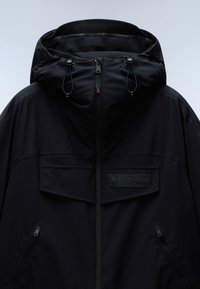 Giacca impermeabile nera con colletto alto, cappuccio regolabile, due tasche con zip e un grande logo sul petto. Tessuto liscio.