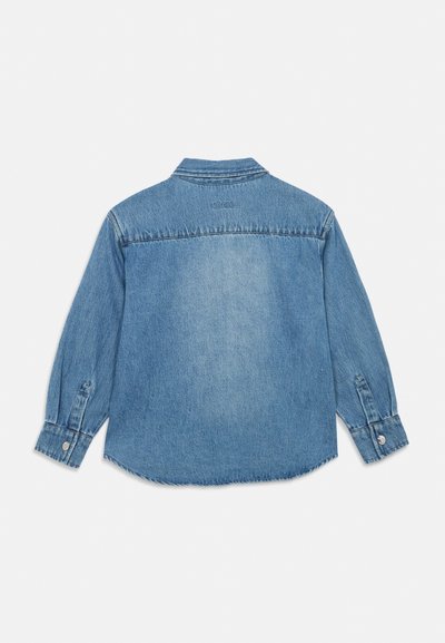 Chemise en denim bleu clair à manches longues vue de dos avec poignets boutonnés et texte brodé subtil sous le col.