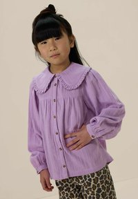 Light purple collared shirt with ruffled edges, button front, and long sleeves. Paired with leopard print pants. Smooth texture.