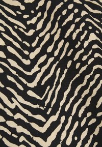 Tissu noir et beige avec des rayures ondulées irrégulières semblables à celles d'un zebra formant un motif imprimé animal abstrait.