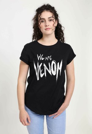 Schwarzes Baumwoll-T-Shirt mit dem Text "WIR SIND VENOM" in fett gedruckter, gezackter weißer Schrift. Mit Rundhalsausschnitt und kurzen Ärmeln gestaltet.