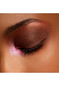 Gros plan sur un œil mettant en valeur un fard à paupières marron profond avec un accent rose vif, une texture lisse et des cils bien définis, sur un teint de peau chaud.