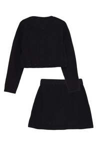 Set di maglione nero cropped e gonna mini, entrambi con una trama spruzzata. Il tessuto è morbido e le silhouette sono semplici e aderenti.