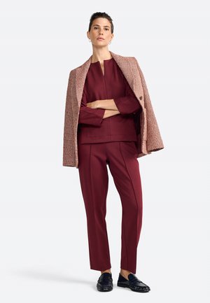 Pantalon et haut bordeaux avec une veste extérieure assortie en tissu texturé ; présente un décolleté simple et une silhouette droite.