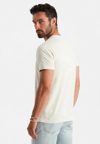 Light beige short-sleeve t-shirt with a subtle textured design, featuring a crew neckline and soft cotton material.
