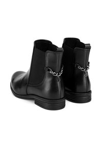 Melnas ādas potītes zābaki ar elastīgām sānu daļām, noapaļota purngala un dekoratīvu ķēdes detaļu ar mazu piekariņu uz papēža.