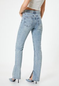 Jeans de tiro alto en azul claro con una silueta ajustada, ligero corte acampanado en el dobladillo y aberturas laterales, fabricados en tejido de mezclilla.