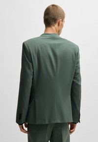 Grüne Anzugjacke aus glattem Stoff. Mit Reverskragen, strukturierten Schultern und Zwei-Knopf-Manschetten. Schlichtes Design, taillierte Passform.