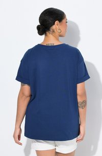 Námornícko modré tričko s krátkým rukávem a ohrnutými rukávy, kulatým výstřihem a volným střihem. Měkká látka s hladkou strukturou.
