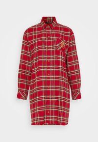 Camicia a scacchi rossi con maniche lunghe, apertura frontale con bottoni e tasca sul petto con dettagli ricamati. Realizzata in tessuto morbido con un motivo a quadri.