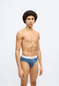 Μπλε ανδρικά εσώρουχα με λευκή ελαστική μέση που διαθέτει το λογότυπο "TOMMY HILFIGER". Κατασκευασμένα από μαλακό ύφασμα, στενή εφαρμογή και απαλή υφή.