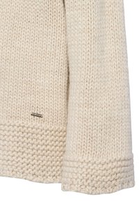 Pull en tricot beige clair, avec un motif texturé. Les poignets présentent un tricot côtelé plus épais, avec une petite étiquette de marque en métal sur l'ourlet.
