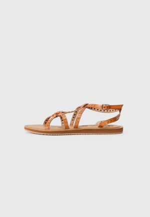 Brown leather sandals with a flat sole, featuring crisscross straps, round studs, and an adjustable ankle buckle.