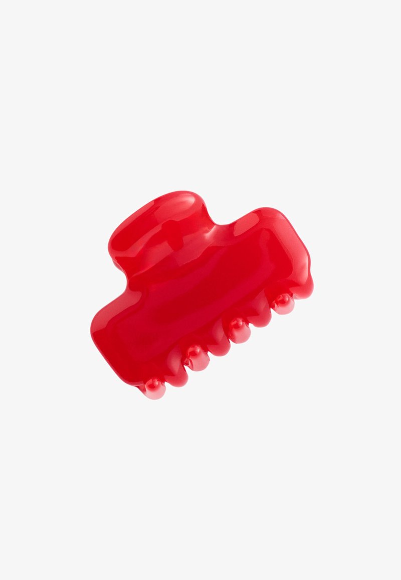 Petite pince à cheveux en plastique rouge avec des dents arrondies et une finition brillante, isolée sur un fond blanc.