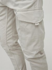 Light beige cargo pants featuring multiple side pockets, visible stitching, and a relaxed fit, made from durable cotton fabric.