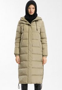Lange gewatteerde jas in licht khaki, met een rits- en knoopsluiting, frontzakken en elastische manchet. Inclusief een afneembare capuchon.