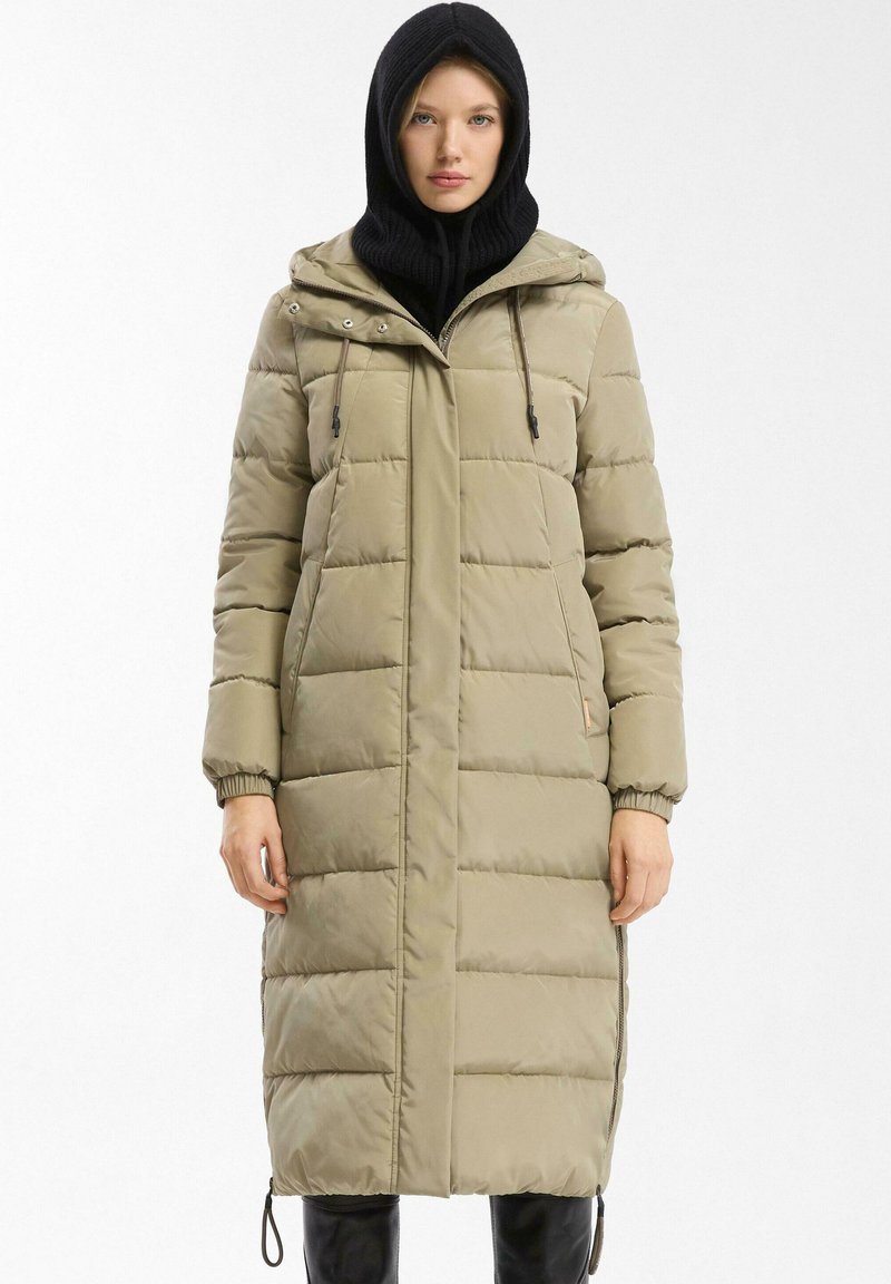 Lange gewatteerde jas in licht khaki, met een rits- en knoopsluiting, frontzakken en elastische manchet. Inclusief een afneembare capuchon.