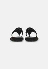 Sorte flip-flops med teksturerte stoffstropper, flate gummisåler og buede tåposter. Enkelt design uten ekstra utsmykkinger.