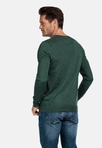 Groene trui met lange mouwen en een gestructureerde afwerking, ronde halslijn, gecombineerd met blauwe jeans, met ribgebreide manchetten en zoom.