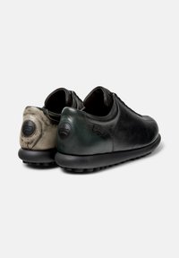 Musta ja tummanvihreä nahkakengät, joissa on teksturoidut pinnat, pyöristetyt taustat ja mustat kumipohjat; niissä on teksturoidut yksityiskohdat ja pyöreät metalliosat.