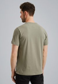 Short-sleeve, olive-green cotton t-shirt with a crew neck and a small rectangular detail on the upper back. Smooth texture and casual fit.