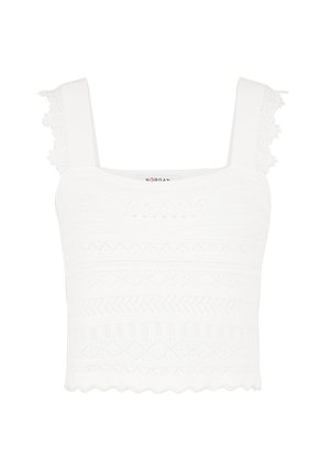 Top court sans manches blanc avec des motifs tricotés texturés, un ourlet festonné et des accents en dentelle décoratifs sur les bretelles.