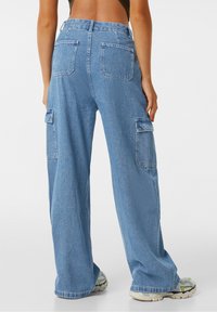 Ljusblå vida cargobyxor med två sidofickor, två bakfickor och synlig sömnad. Tillverkade av denim med en avslappnad passform.