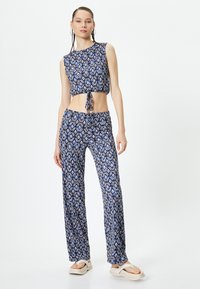 Twee-delige outfit met een cropped, mouwloze top en losse broek, beide in een blauw diamantpatroon met witte accenten.