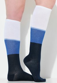 Collant al ginocchio con texture a coste, in blocchi di colore bianco, azzurro chiaro, blu scuro e blu navy, che mostrano sezioni geometriche distintive.