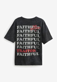 Zwarte katoenen T-shirt met korte mouwen. Kenmerkt zich door vetgedrukte tekst: "FAITHFUL," "TRAITOR" in het rood en "THE TRAITORS" in het wit, allemaal in een verouderde stijl.