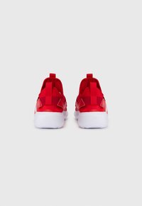 Rote Sportschuhe mit strukturiertem Obermaterial, hinteren Zuglaschen und weißen Gummisohlen. Verfügt über kontrastierende Akzente in dunklerem Rot und ein elegantes Design.