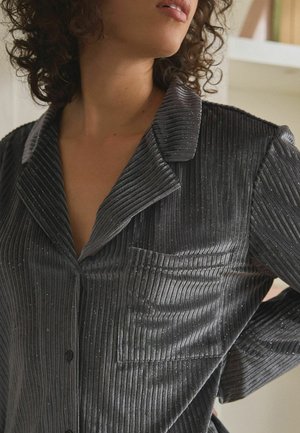 Gray ribbed shirt made of velvet with a subtle sparkly finish. Features a collar, buttons, and a pocket on the left side.