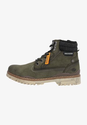 Stivali alla caviglia in suede verde scuro con un colletto in tessuto grigio, occhielli in metallo nero, etichetta arancione e suola in gomma beige robusta.