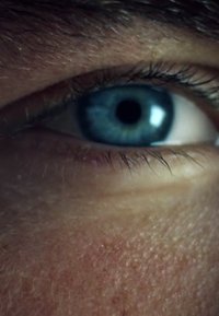 Gros plan d'un œil bleu avec une pupille foncée, de fins cils et une texture de peau détaillée autour de l'œil, mettant en valeur des nuances et des éléments variés.