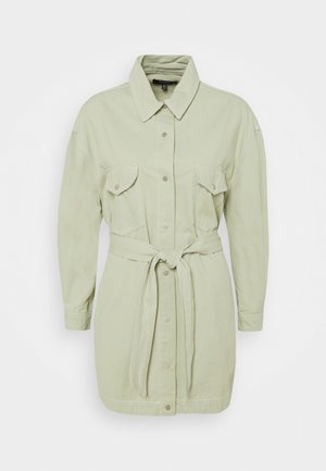 Robe-chemise vert clair à manches longues avec col, fermeture boutonnée à l'avant, deux poches à rabat sur la poitrine et ceinture en tissu nouée à la taille.
