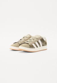 Beiga och gröna sneakers har en kamouflage-design, vita ränder, en texturerad ovandel och en sula i gummirubber.