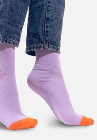 Fioletowe skarpetki z pomarańczowym czubkiem, wykonane z gładkiego materiału. Projekt ma klasyczną długość crew i dopasowany kształt.