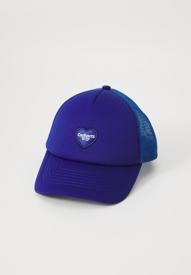 Lila Kappe mit einem blauen Netzrückenteil, versehen mit einem herzförmigen Aufnäher mit "Carhartt WIP" in weißem Text. Strukturiertes Design mit Nähdetails.