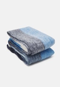 Couverture en laine aux nuances de bleu et gris, pliée. Texture douce avec un mélange de couleurs et de motifs, présentant des finitions lisses et duveteuses.